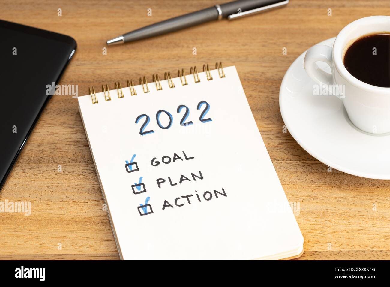 Neujahr 2022 Ziel, Plan, Aktionstext auf Notizblock und Kaffeetasse und Smartphone auf Holztisch. Konzept zur Geschäftsmotivation Stockfoto