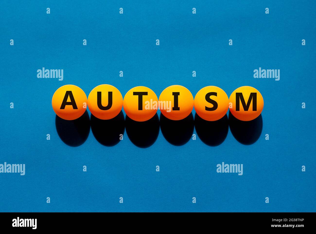 Symbol für Medizin und Autismus. Das Konzeptwort „Autismus“ auf orangefarbenen Tischtennisbällen auf einem schönen blauen Hintergrund. Medizinische, psychologische und Autismus Co Stockfoto