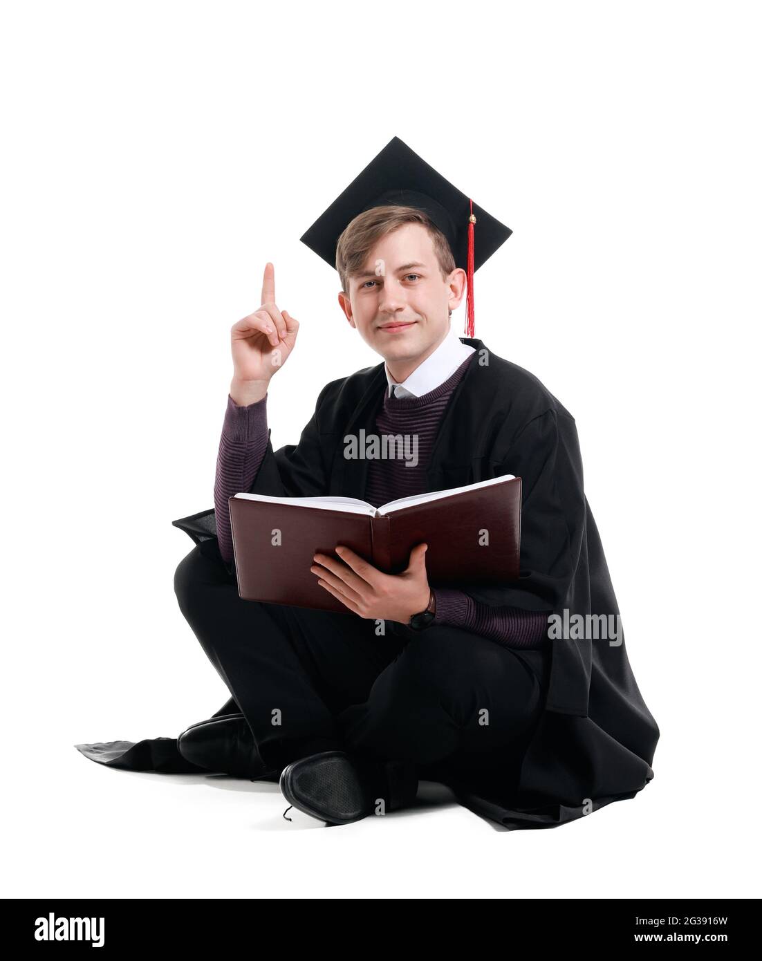 Männlicher Student mit Buch und erhobenem Zeigefinger auf weißem Hintergrund Stockfoto