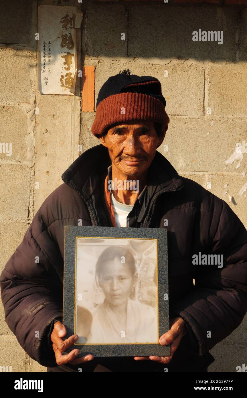 Zhang Zhengbi, 74 Jahre alt, mit einem Foto seiner geliebten burmesischen Frau, die vor 8 Jahren starb. Die Erinnerung, als seine Eltern und Geschwister getötet wurden, bevor er im Alter von 17 Jahren die Stadt Longling verließ, ist immer noch lebendig in seinem Kopf. Er versuchte jahrzehntelang, Briefe an seinen Neffen zu schicken, den einzigen Verwandten, den er verlassen hat, bis er Erfolg hatte. Dennoch werden sich Träume, seinen Neffen zu besuchen und Gräber für seine Familienmitglieder zu bauen, von den senilen Krankheiten und seinem armutsbetroffenen Leben nie erfüllen. Chiang Rai, Thailand. 24. Januar 2009. Teil der Fotofeature, Exil Kuomintang Rückkehr nach Mutterland, durch Stockfoto