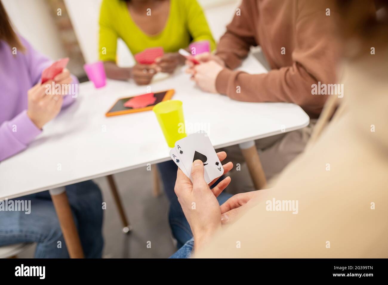 Hände junger Menschen mit Karten, die am Tisch sitzen Stockfoto