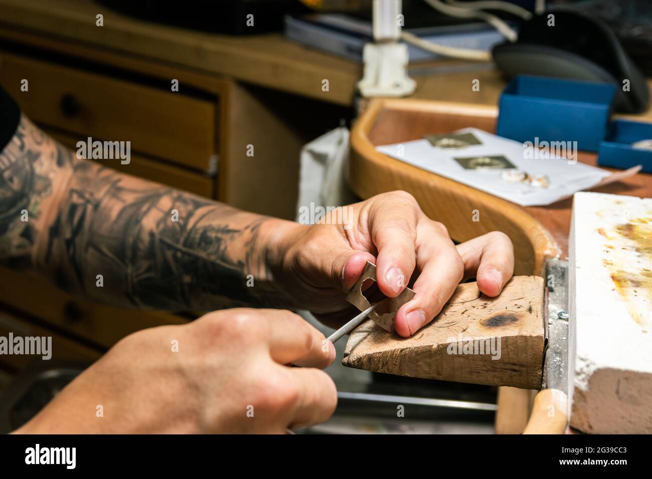 Mann in der Schmuckwerkstatt, der ein Stück Silber einreicht. Stockfoto