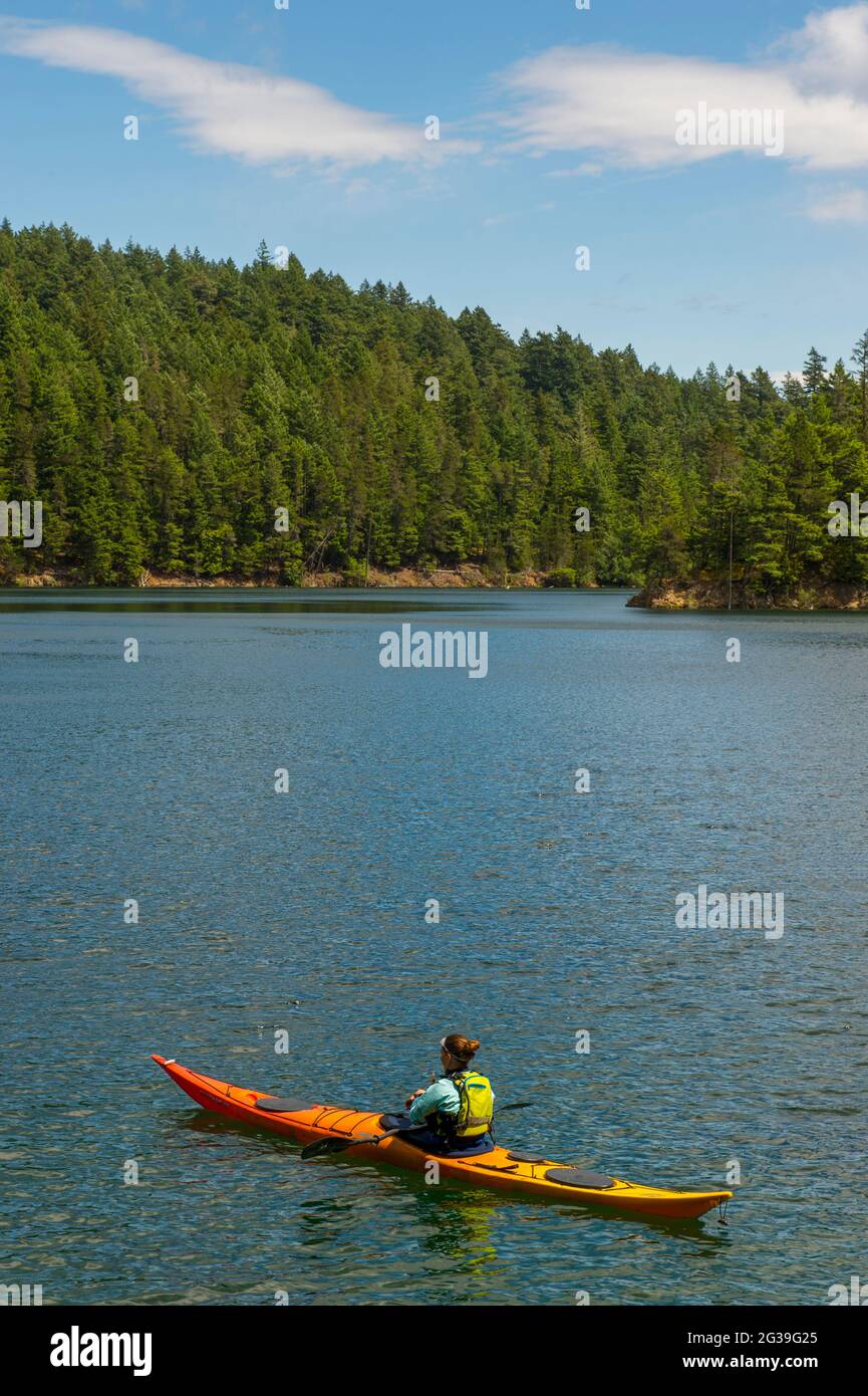 Eine Frau fährt mit dem Kajak auf dem Mountain Lake im Moran State Park auf der Orcas Island, San Juan Islands im US-Bundesstaat Washington. Stockfoto