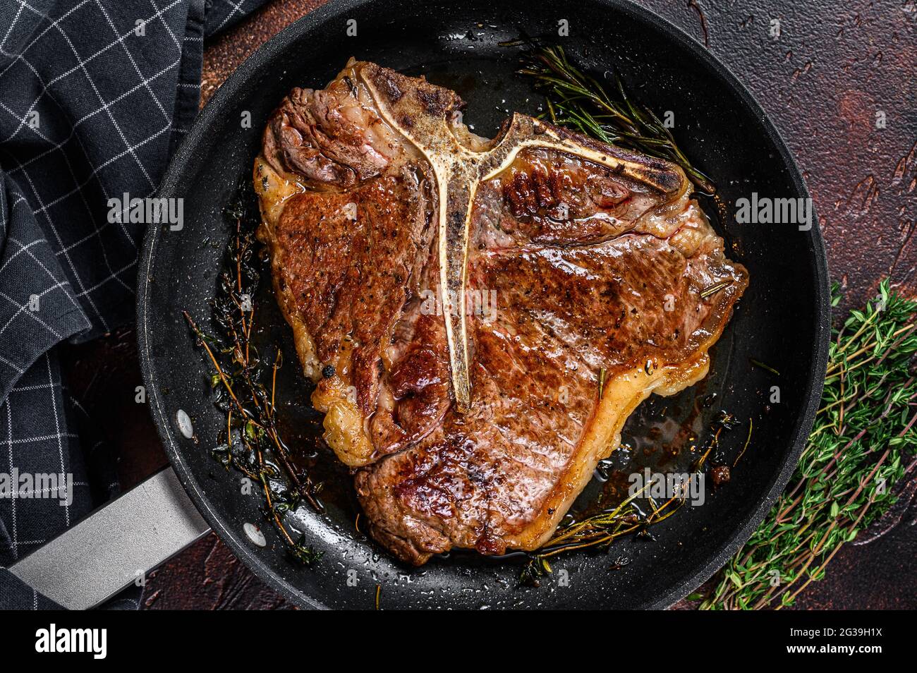 Gegrilltes Porterhouse-Rinderfleisch Steak mit Kräutern in einer Pfanne.  Dunkler Hintergrund. Draufsicht Stockfotografie - Alamy