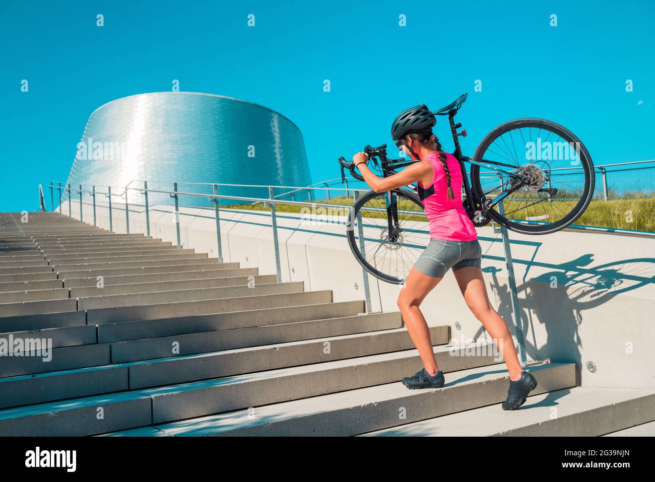 Stadtradfahrer, die in der Stadt mit dem Fahrrad unterwegs sind, gehen die Treppen hoch, während man in der Innenstadt pendeln kann Stockfoto