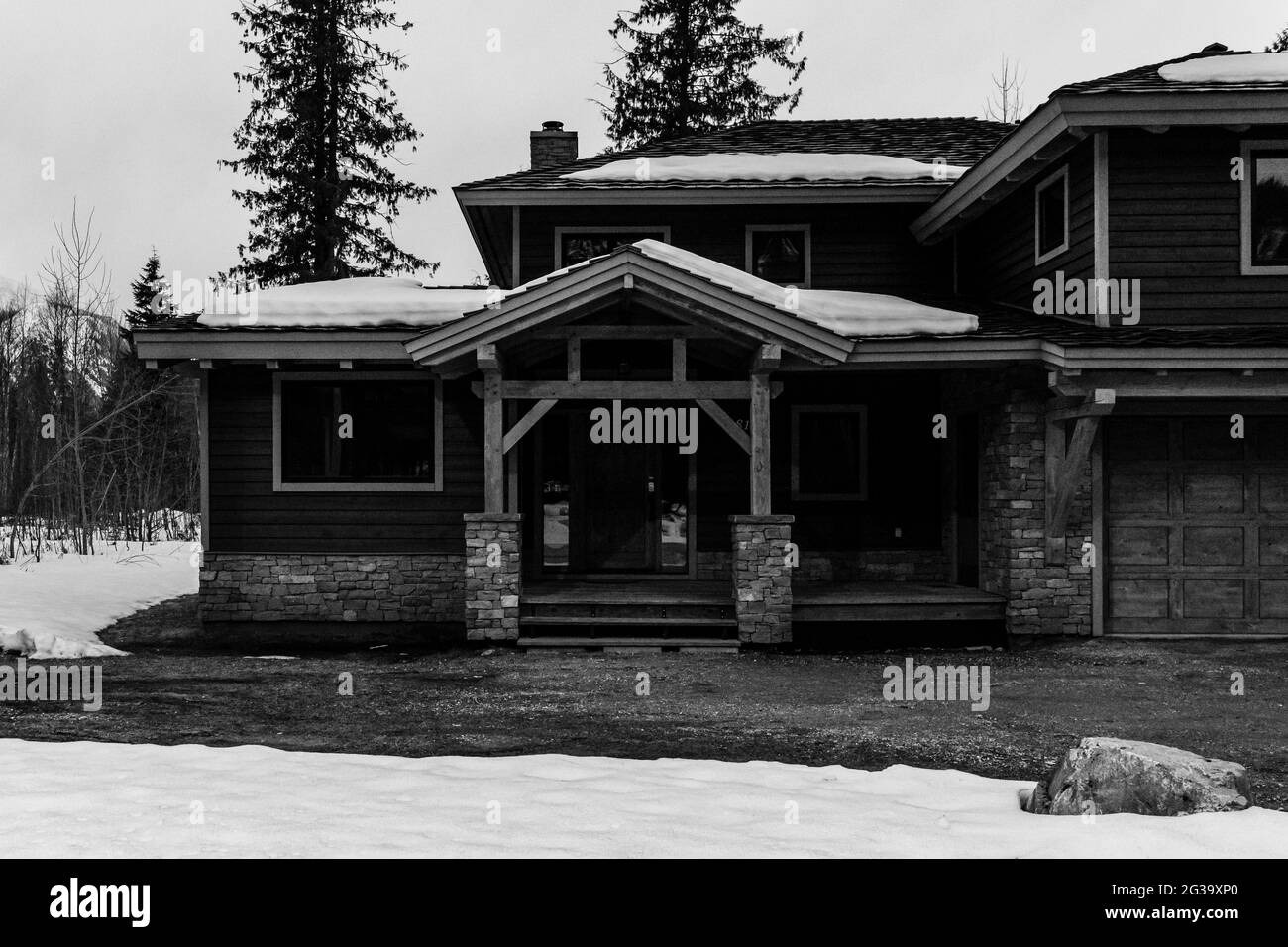 REVELSTOKE, KANADA - 14. MÄRZ 2021: Schwarz-weißes Privathaus in Kleinstadt Abendzeit früher Frühling mit Schnee Stockfoto