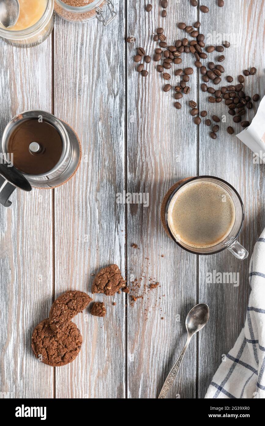 Eine Tasse frisch gebrühten Kaffee mit Schokolade-Shortbreads, gerösteten Kaffeebohnen und Mokakapfanne auf einem Holzhintergrund. Kinfolk-Stil. Flach liegend Stockfoto