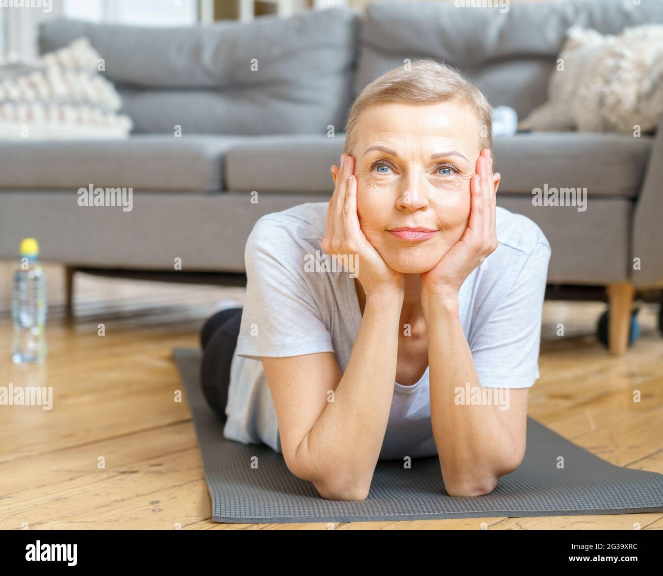 Ältere Frau lächelt während des Trainings zu Hause vor der Kamera Stockfoto