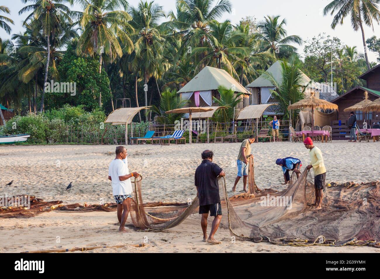 Indische Fischer, die am Strand, Agonda, Goa, Indien, zu ihren Fischernetzen tendieren Stockfoto