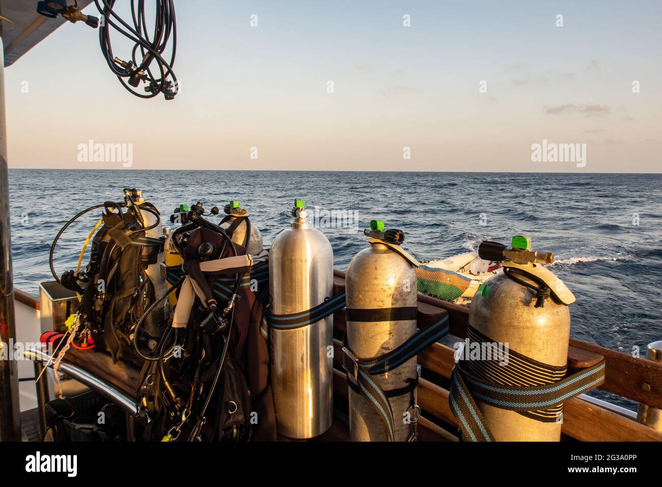 Tauchausrüstung mit Tanks, BCDs, Regulatoren, Gewichtsgurte montiert, auf einem Tauchboot mit Meerblick im Hintergrund, Rotes Meer, Sudan. Stockfoto