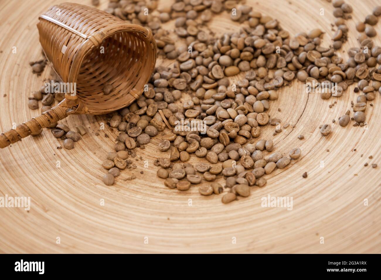 Trockene grüne Kaffeebohnen und Weidenbecher lagen auf einem Holztisch Stockfoto