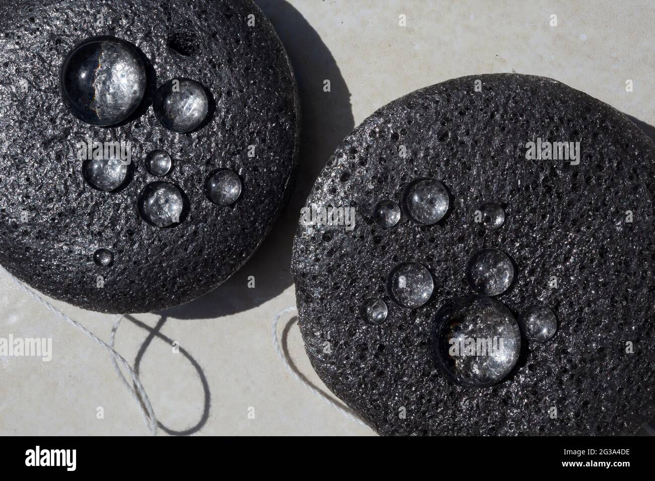 Bambuskohlenstoffschwamm in Nahaufnahme mit Wassertropfen. Gesichtsreinigung und Make-up Entfernen Beauty Routine Stockfoto