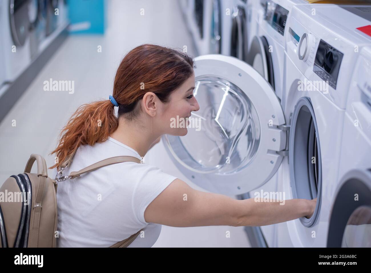 Kaukasische Frau wählt eine Waschmaschine in einem Haushaltswarenladen Stockfoto