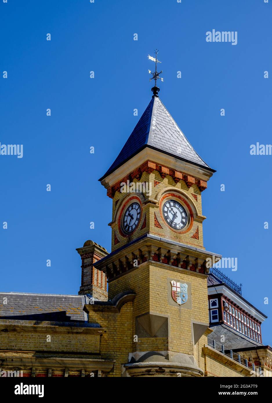 Staycation Idee. Eastbourne Railway Station Uhrenturm, mit Wappen, gegen einen wolkenlosen blauen Himmel. East Sussex, Großbritannien Stockfoto