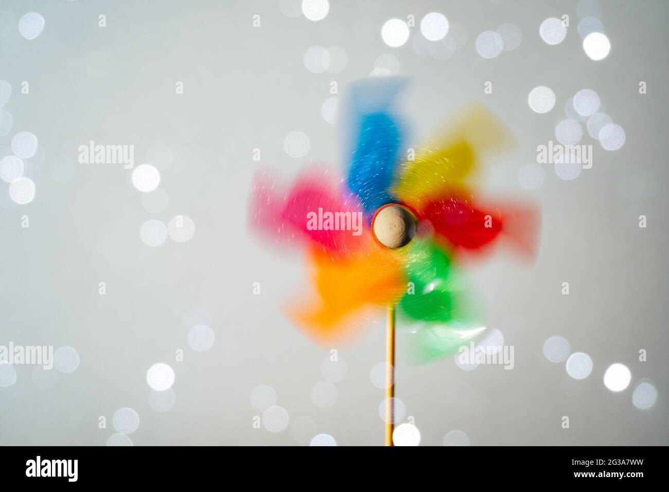 Farbenfroh drehendes Windrad auf glänzendem weißem Hintergrund. Sommerspaß Stockfoto