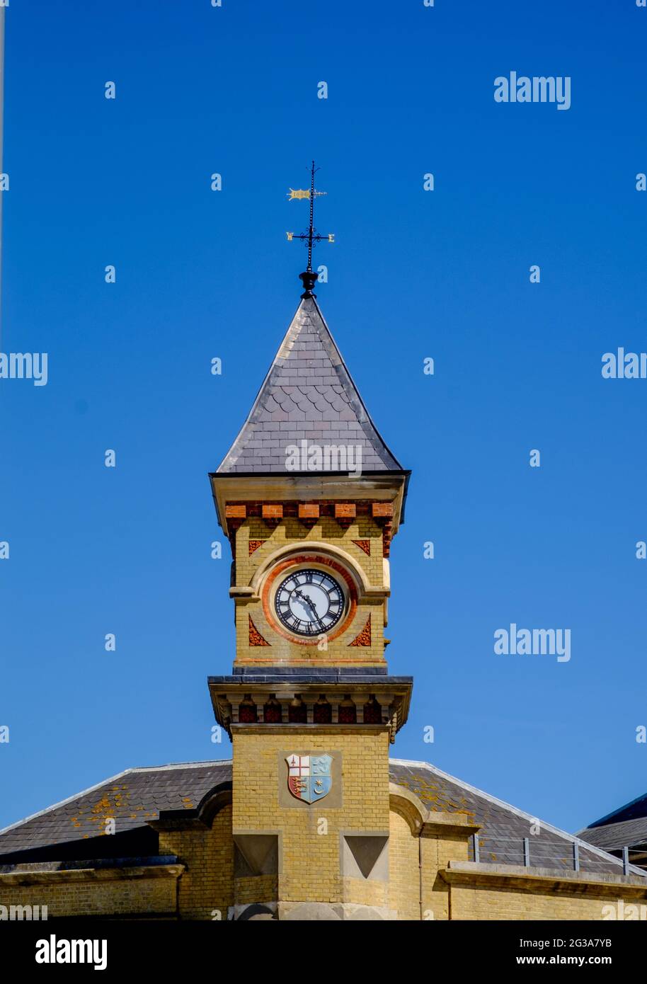 Staycation Idee. Eastbourne Railway Station Uhrenturm, mit Wappen, gegen einen wolkenlosen blauen Himmel. East Sussex, England, Großbritannien Stockfoto