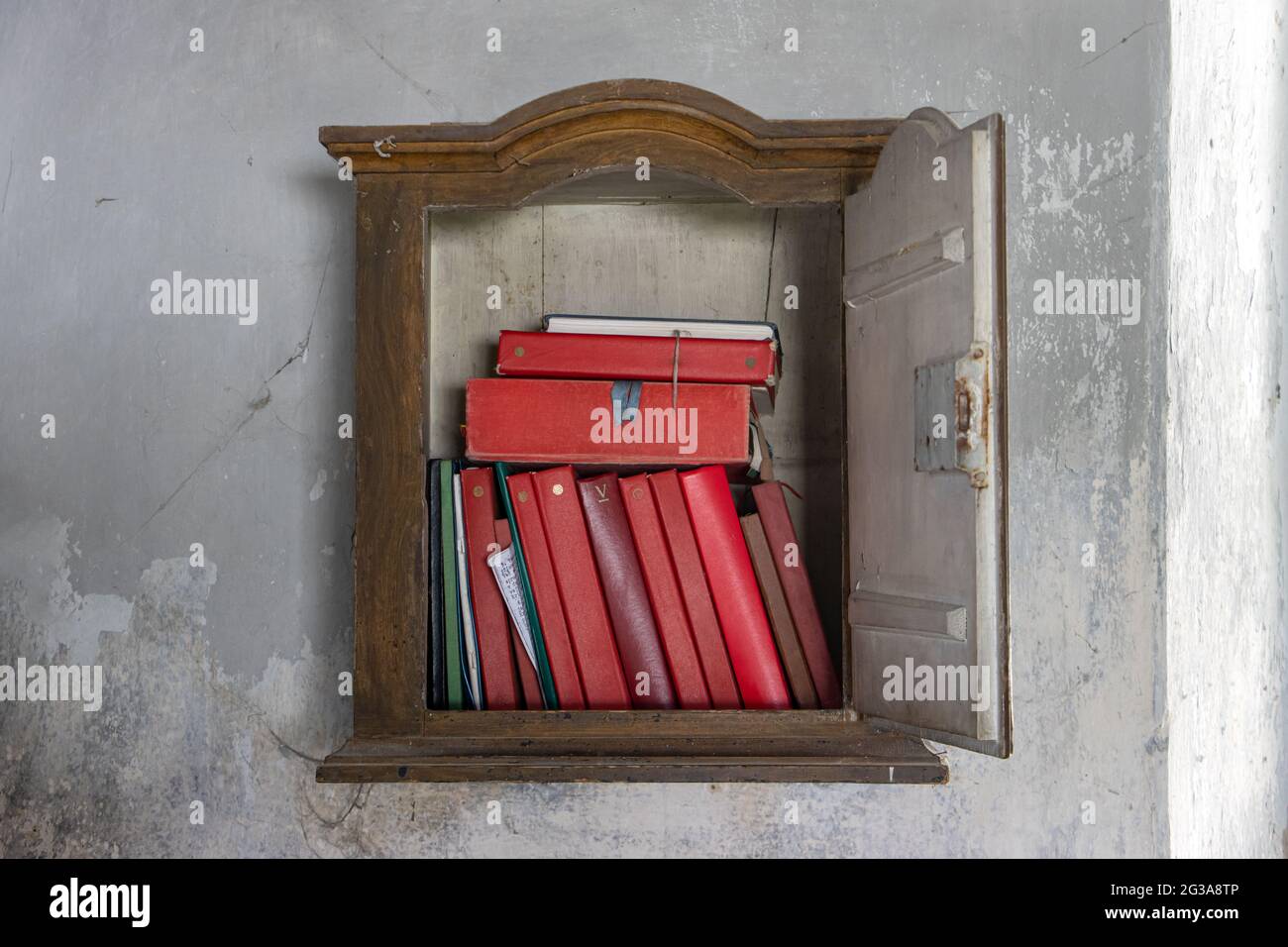 Die religiöse Literatur in der alten Bibliothek hängt an der Wand in der Sakristei der Kirche. Stockfoto