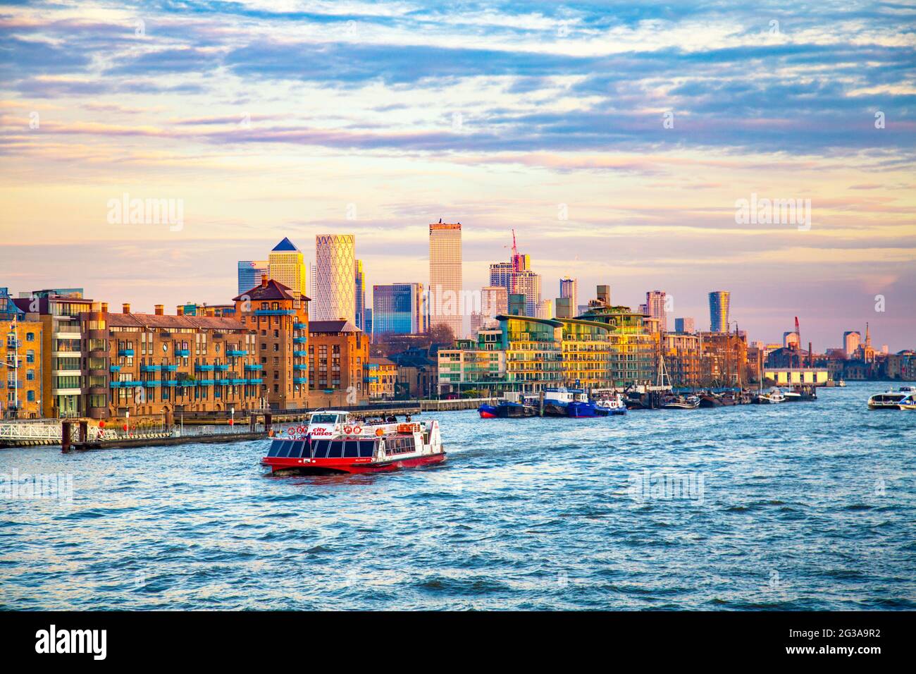 Blick auf East London von der Tower Bridge, Lagerhallen von Wapping und Canary Wharf Wolkenkratzer bei Sonnenuntergang, City Cruises Tour Boot auf der Themse, Londo Stockfoto