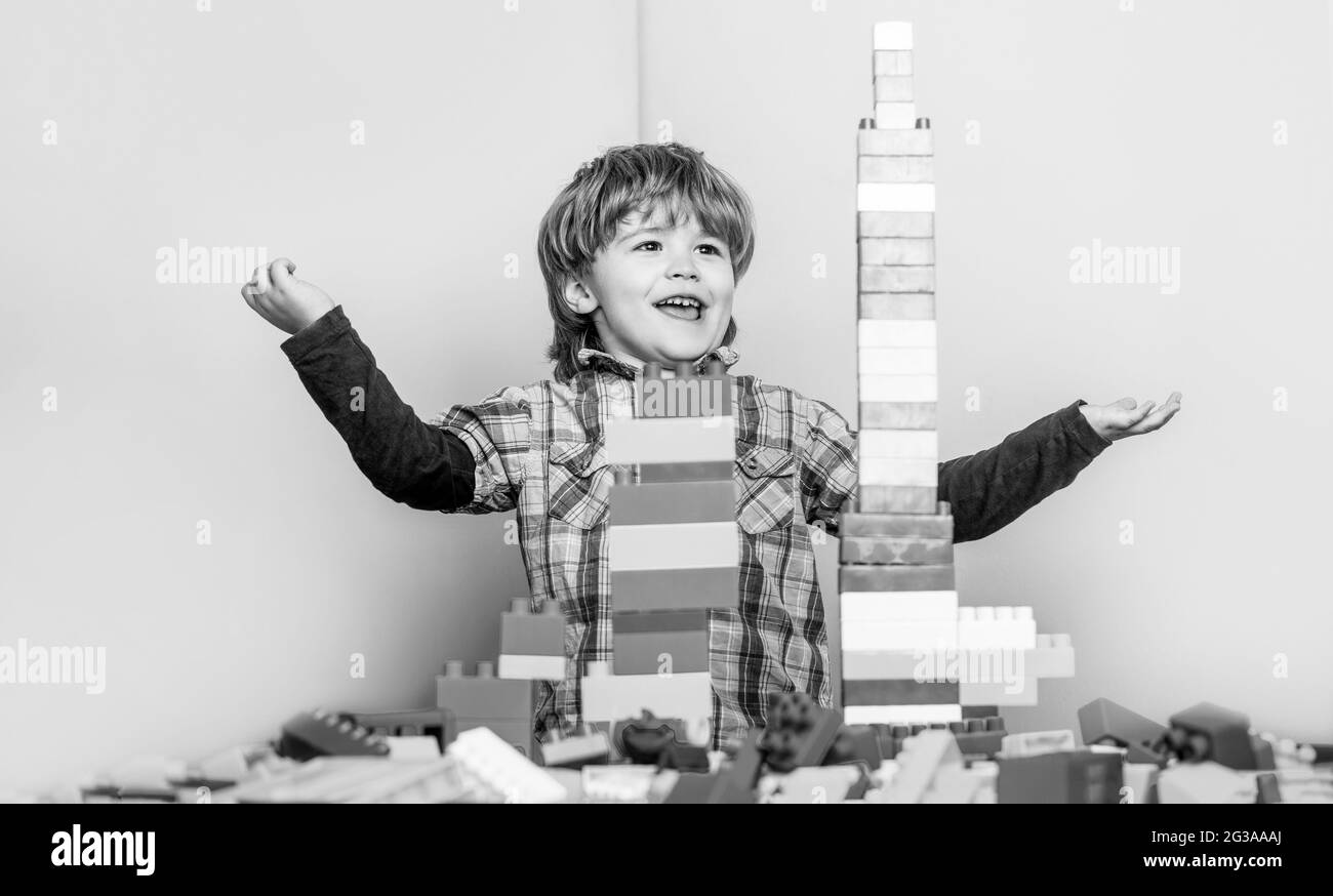 Junge spielt mit Bausteinen im Kindergarten. Kind spielt mit bunten Spielzeugblöcken. Pädagogisches Spielzeug für kleine Kinder. Schwarz und Weiß Stockfoto