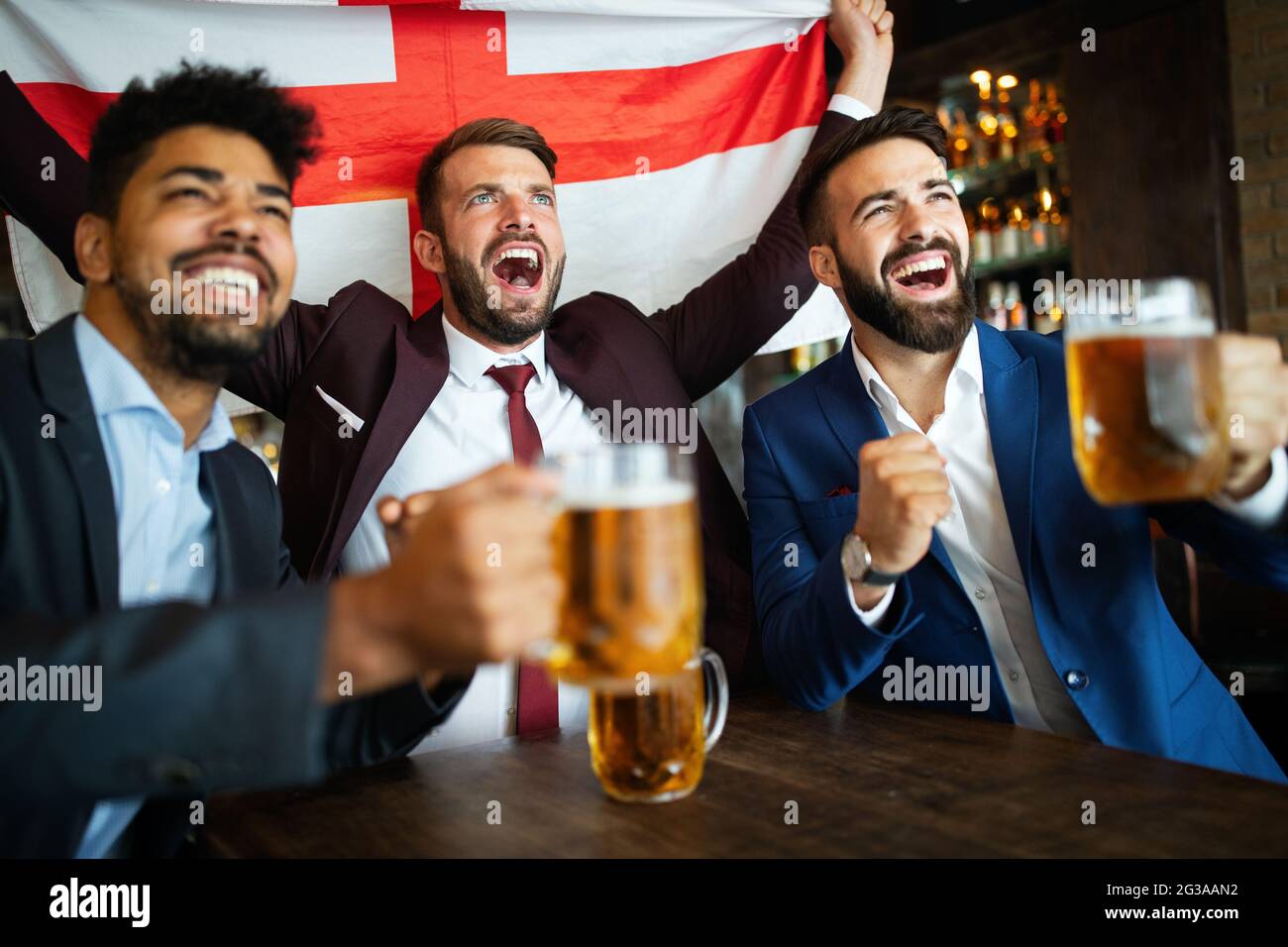 Männerfans schreien und beobachten Fußball im Fernsehen und trinken Bier in einer Kneipe Stockfoto
