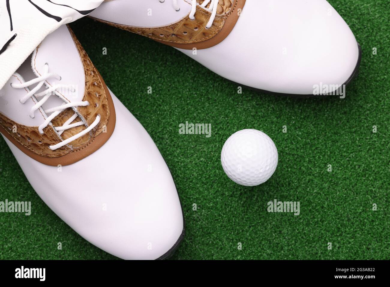 Weiße Schuhe und Ball liegen in der Nähe auf dem grünen Golfplatz Stockfoto