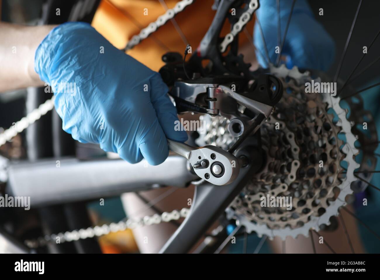 Handschuhen, die Fahrradkette mit Werkzeugen aus der Nähe befestigen Stockfoto