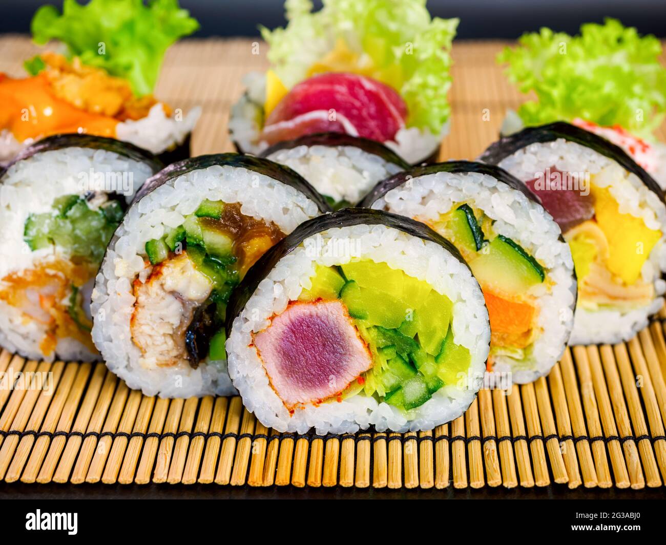 Set von Sushi-Rollen auf Bambusmatte auf schwarzem Hintergrund.  Verschiedene Maki-Sushi-Rollen mit Thunfisch, Lachs, Aal, Gurke und Avocado  Stockfotografie - Alamy