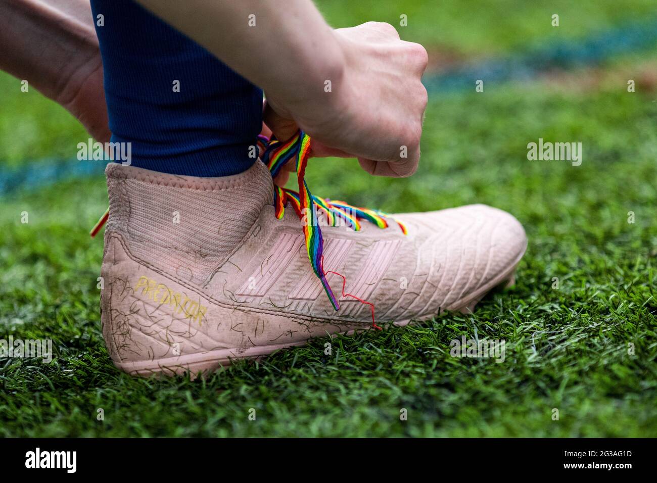 Ein Fußballer schnürt Stonewall's Rainbow Laces auf einem Adidas Predator Fußballschuh. Stockfoto