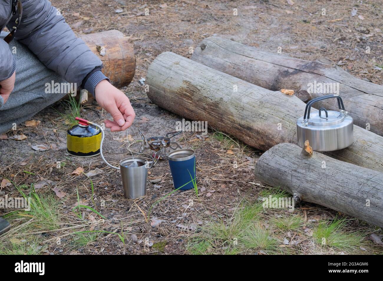 Touristische Küche für Outdoor-Aktivitäten. Der Reisende macht während des Campens Tee in einem Becher. Genießen Sie ein leckeres Essen während Wanderungen. Stockfoto