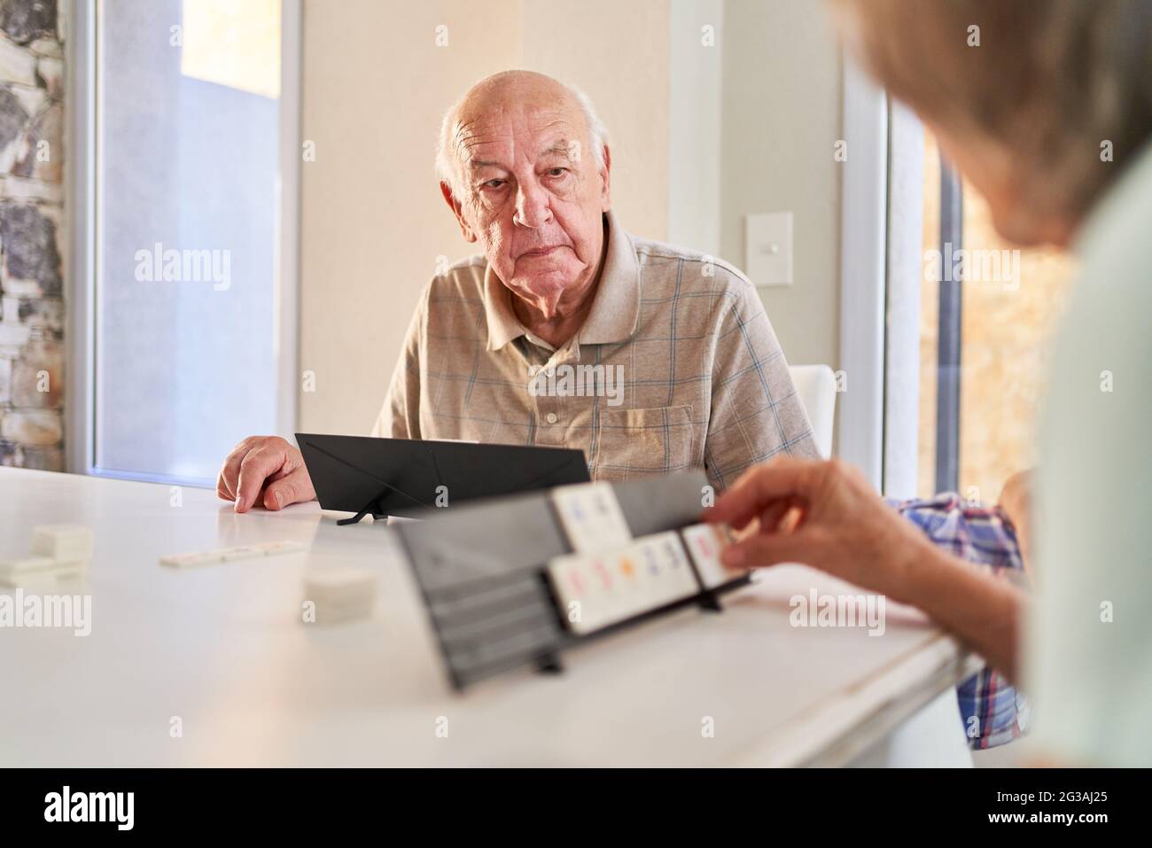 Senioren mit Demenz spielen im Rummikub als Gehirnteaser und Gedächtnistraining im Pflegeheim Stockfoto