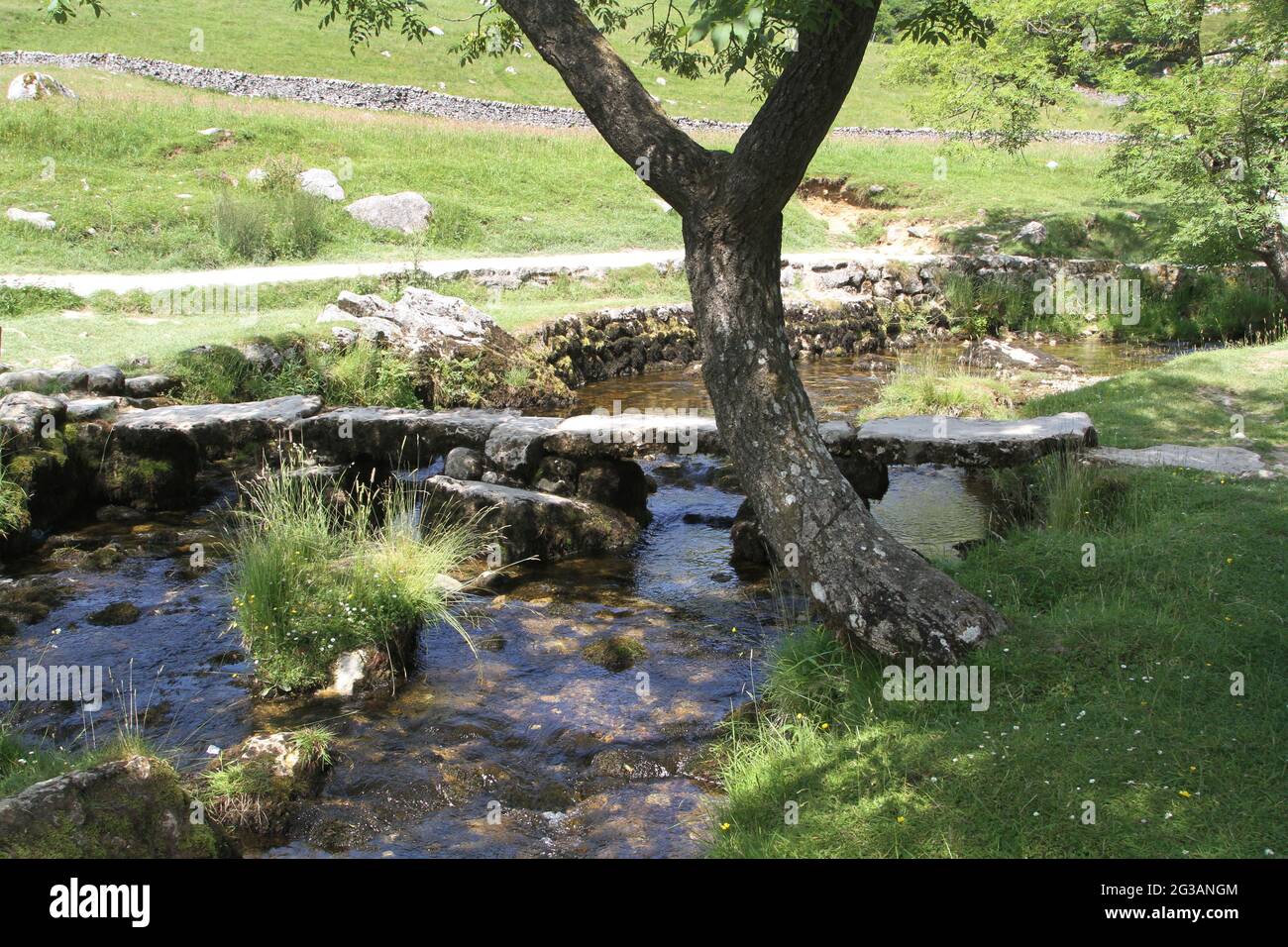 Antiker Fluss, der eine Klappbrücke überquert, Malham, Yorkshire, England Stockfoto