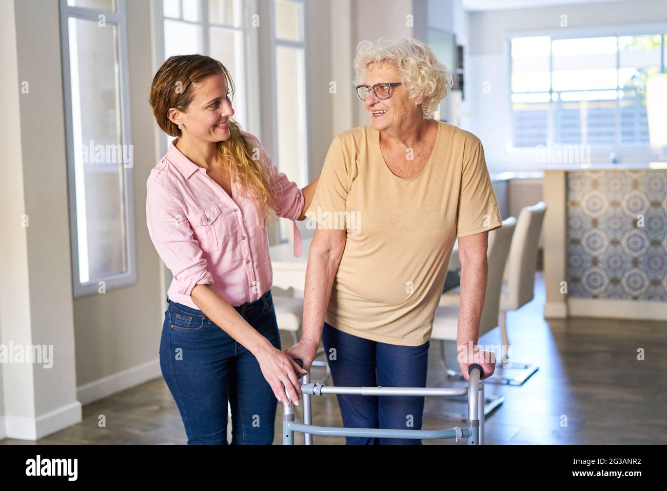 Fürsorgliche junge Frau, die sich um die ältere Mutter kümmert, die nach einem Schlaganfall zu Fuß geht Stockfoto