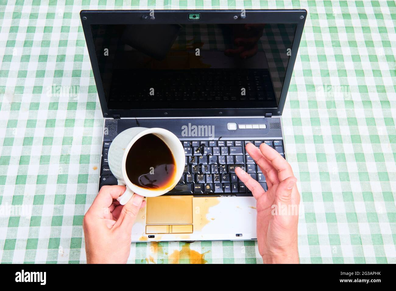 Notizbuch schüttete ungemülich Kaffee aus einer Tasse. Computerunfall. Laptop mit Flüssigkeit zerstört. Kaffee verschüttet auf Laptop-Tastatur. Verschütten von Kaffee Stockfoto