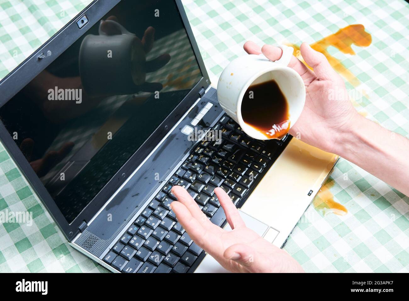 Notizbuch schüttete ungemülich Kaffee aus einer Tasse. Computerunfall. Laptop mit Flüssigkeit zerstört. Kaffee verschüttet auf Laptop-Tastatur. Verschütten von Kaffee Stockfoto