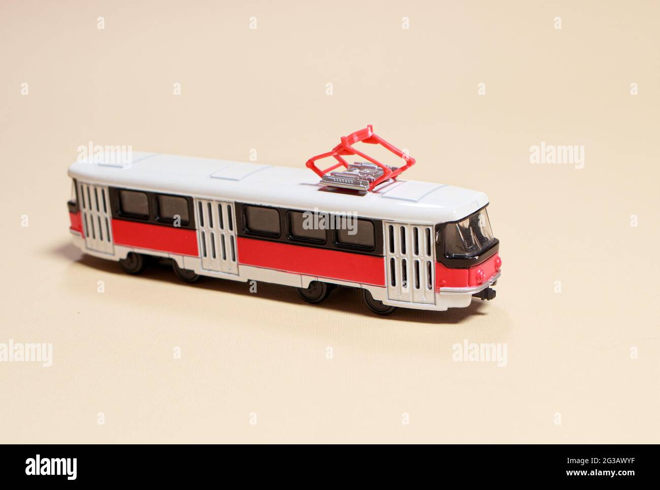 Kinderspielzeug rot weiß Tram auf einem beigen Hintergrund Kopie Platz für Text. Spielzeug für einen Spielwarenladen, Autos für einen Jungen. Stockfoto