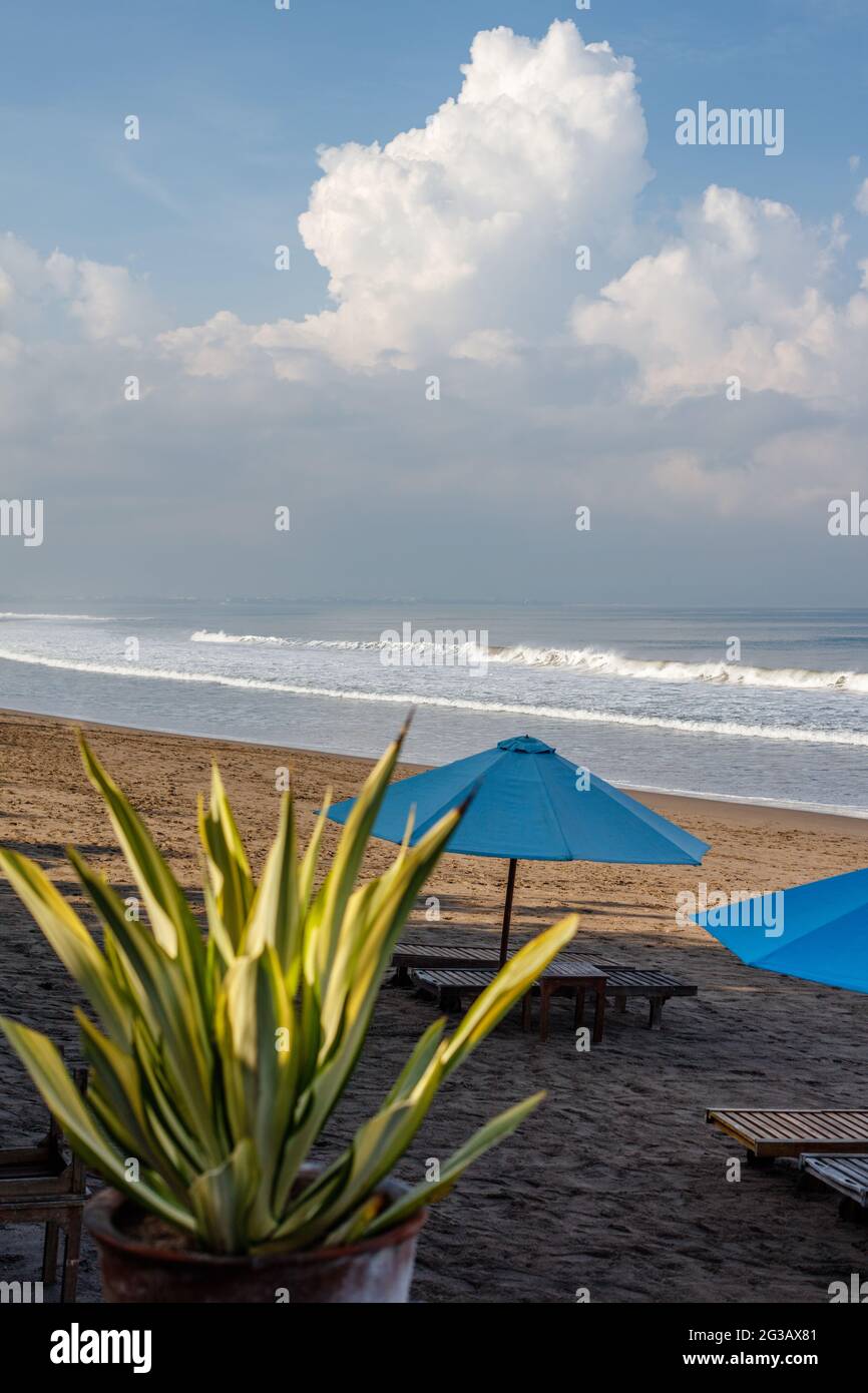 Batu Belig Beach (Pantai Batu Belig), Badung, Bali, Indonesien. Grauer Sand, Sonnenschirme, Meereswellen, blauer Himmel mit Wolken. Stockfoto