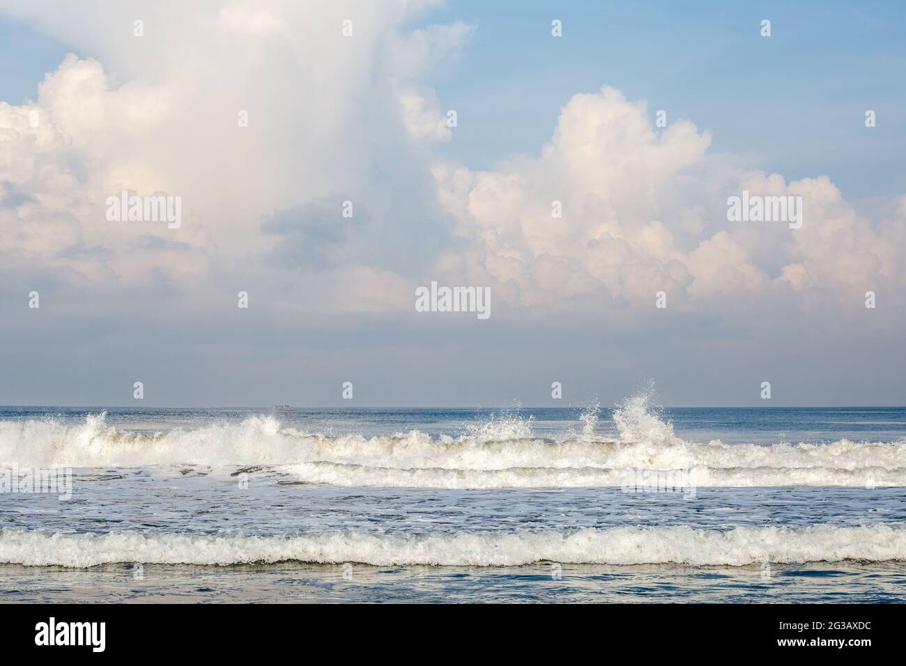 Batu Belig Beach (Pantai Batu Belig), Badung, Bali, Indonesien. Grauer Sand, Meereswellen, blauer Himmel mit Wolken. Stockfoto