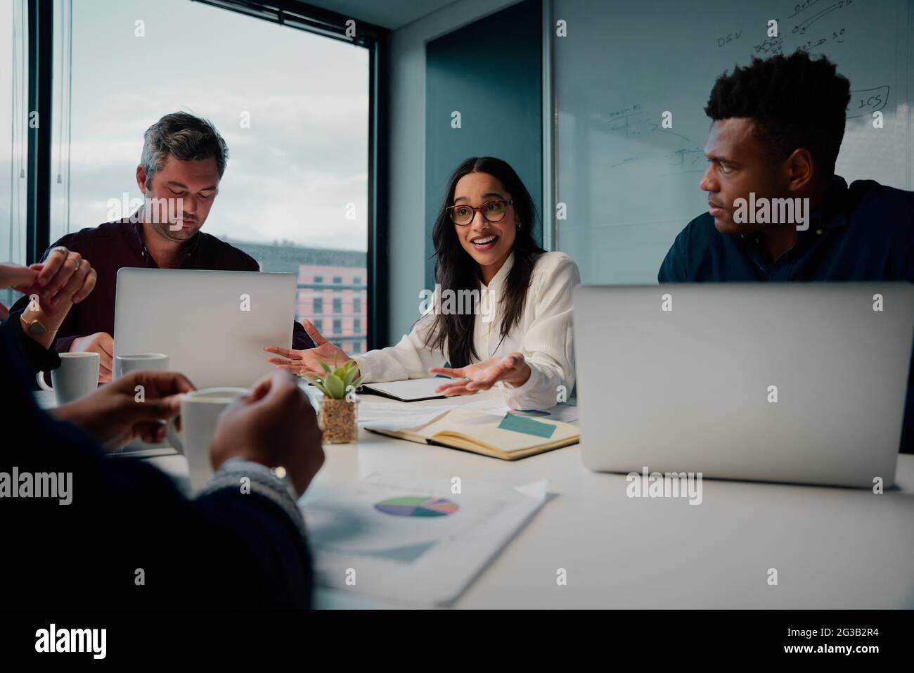 Junge Geschäftsfrau, die im modernen Büro mit ihren männlichen Kollegen diskutiert Stockfoto