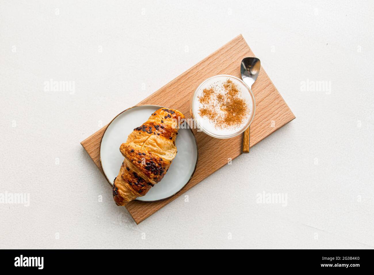 Glas Kaffee Latte mit Zimt und Croissant Stockfoto