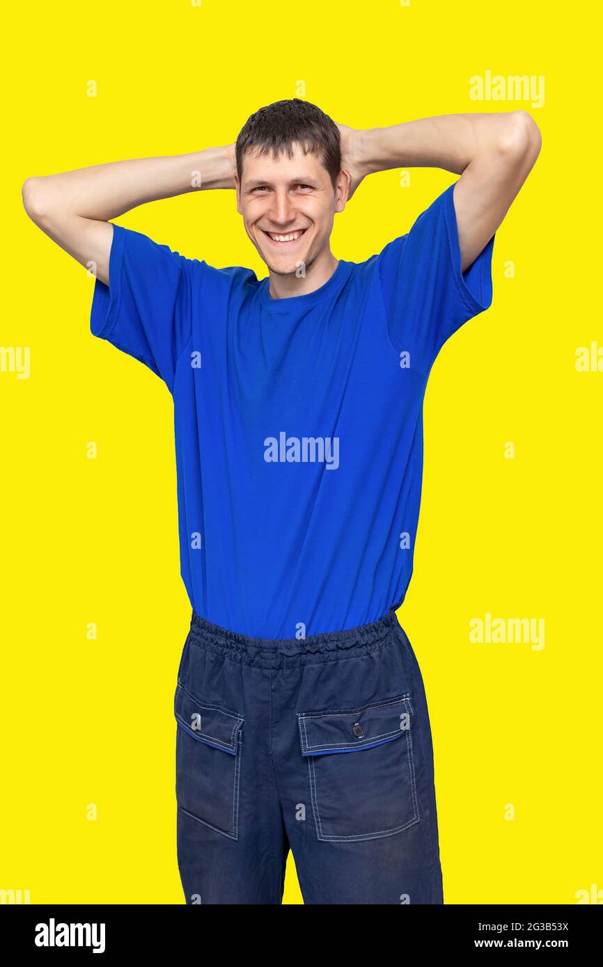 Werbung für Arbeitskleidung. Der positive Kerl lächelt und hält seine Hände  hinter seinem Kopf. Isoliertes Porträt auf gelbem Hintergrund  Stockfotografie - Alamy