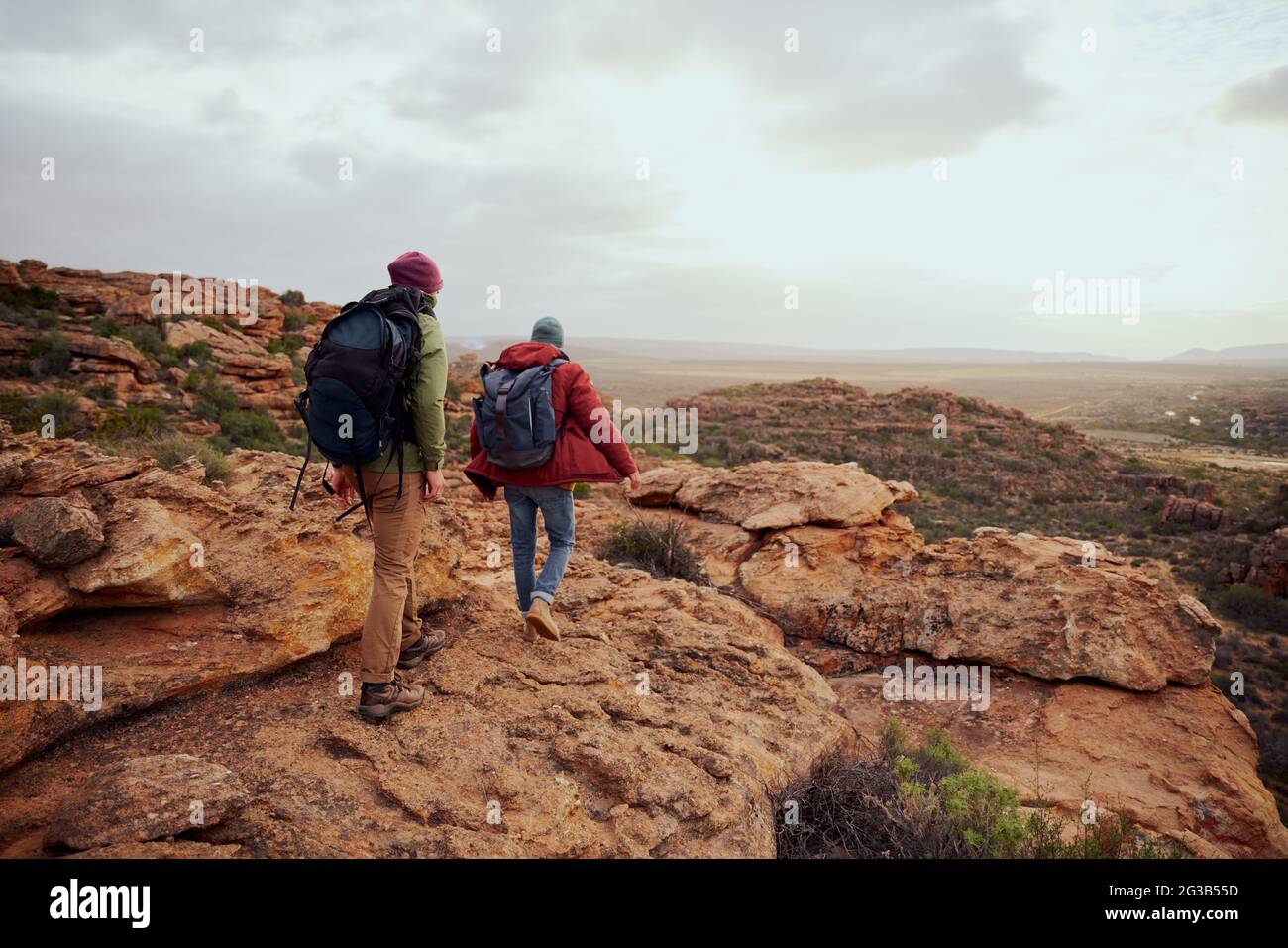 Rückansicht von jungen männlichen Wanderfreunden, die mit Rucksack den Berg erklimmen Stockfoto