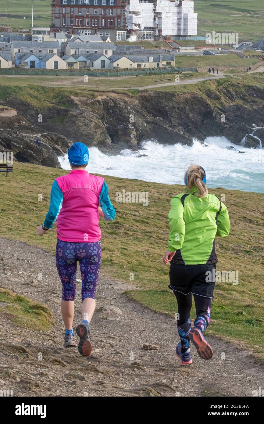 Zwei Freundinnen, die auf Towan Head in Newquay im Rahmen ihres Keep-FIT-Regimes einen rauen Fußweg hinunterlaufen. Stockfoto