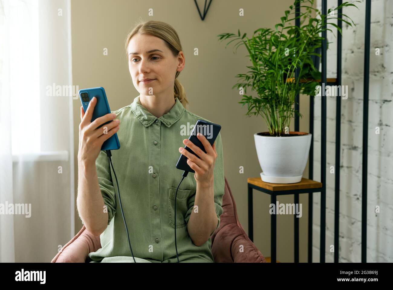 Frau überträgt Daten von einem alten auf ein neues Telefon mit Kabelverbindung Stockfoto