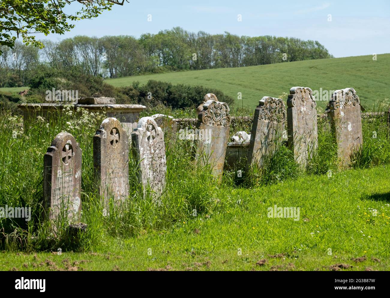 Auf dem Friedhof der St. Peter's Church in Rodmell bei Lewes in East Sussex, Großbritannien, stehen in Reihe alte Grabsteine Stockfoto