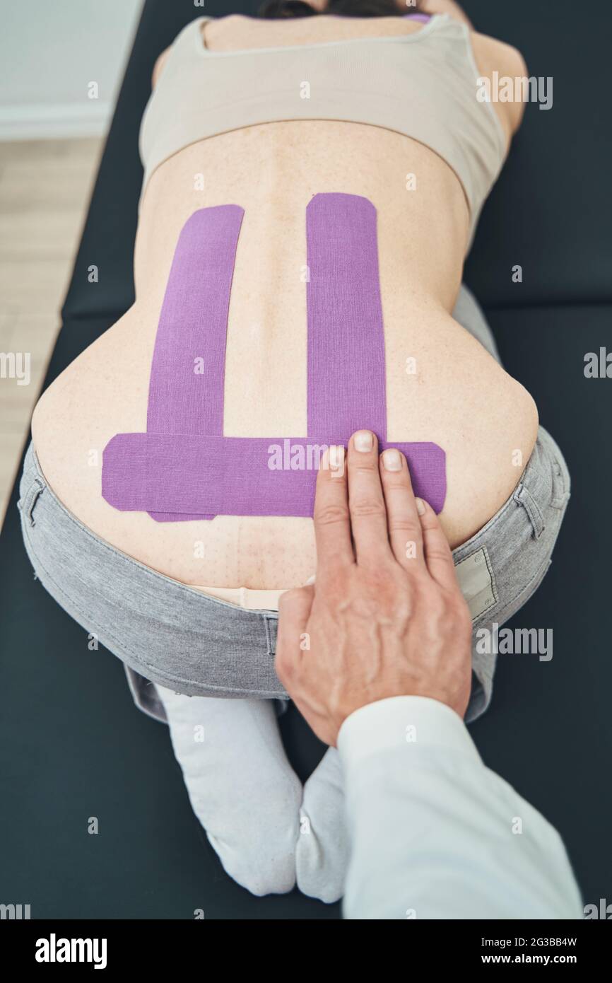 Arzt, der ein elastisches therapeutisches Band für Schmerzen im unteren Rücken verwendet Stockfoto