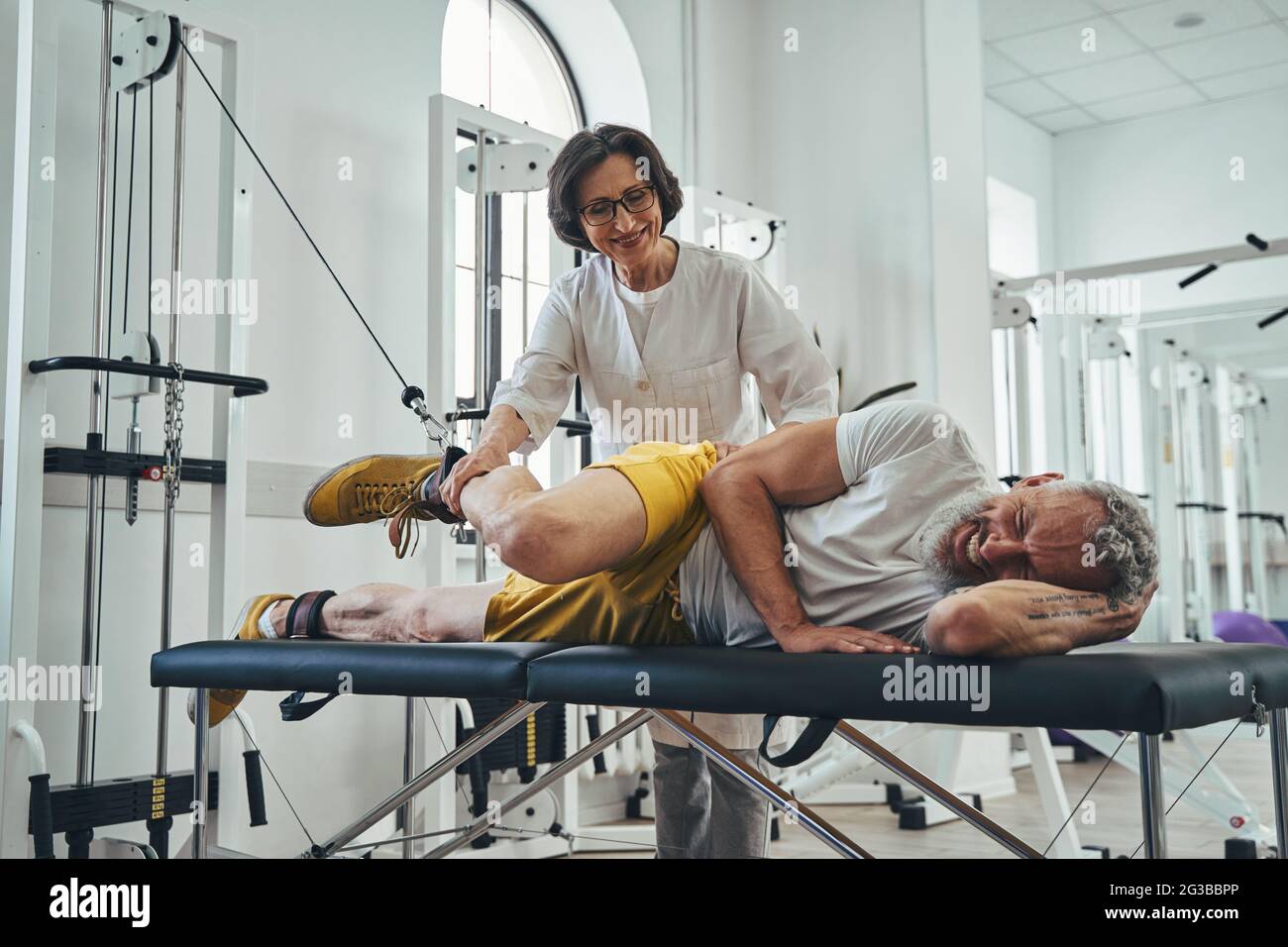 Ein Mann, der ein seitliches Bein hebt, wird von einem Arzt unterstützt Stockfoto