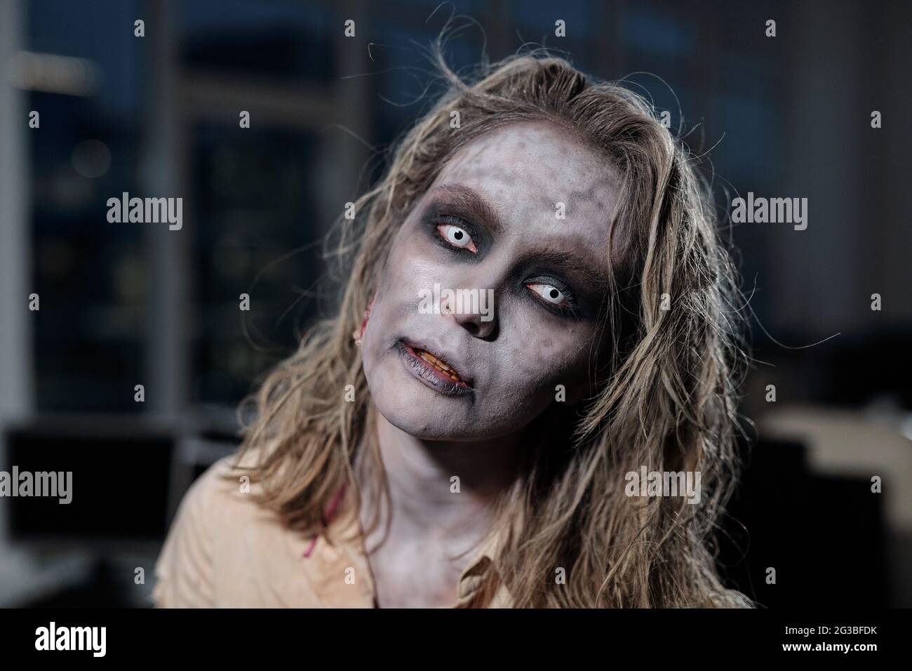 Zombie-Hündin, die vor der Kamera im dunklen Raum oder Büro steht Stockfoto