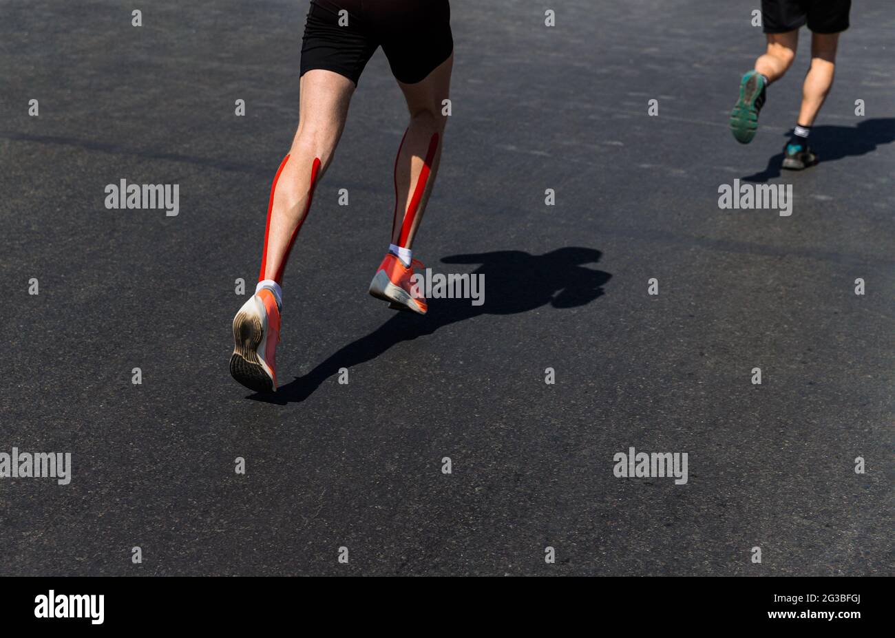 Beine zwei männliche Läufer laufen Marathon auf dunklem Asphalt Stockfoto