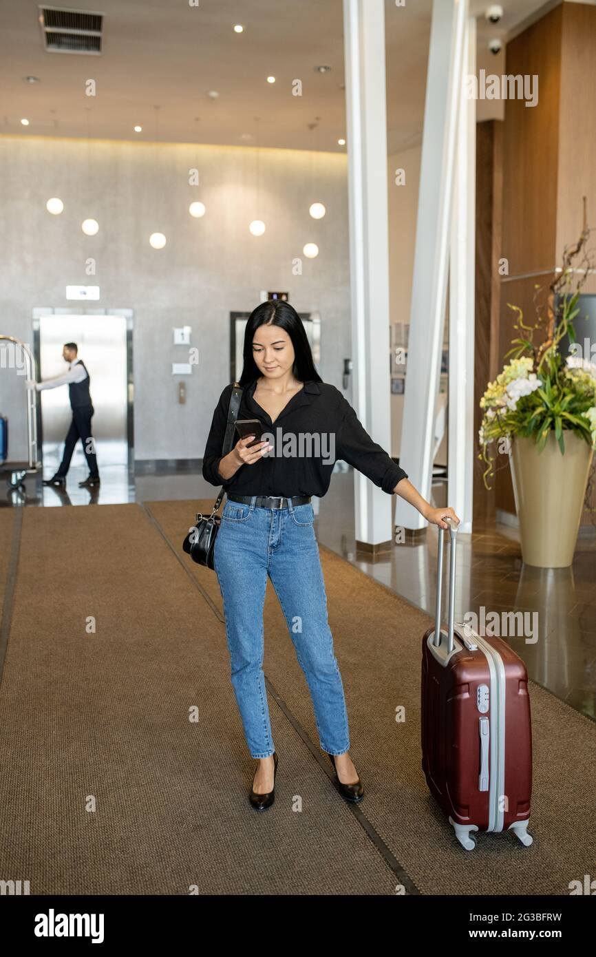 Junge attraktive Geschäftsfrau mit Smartphone am Flughafen Stockfoto