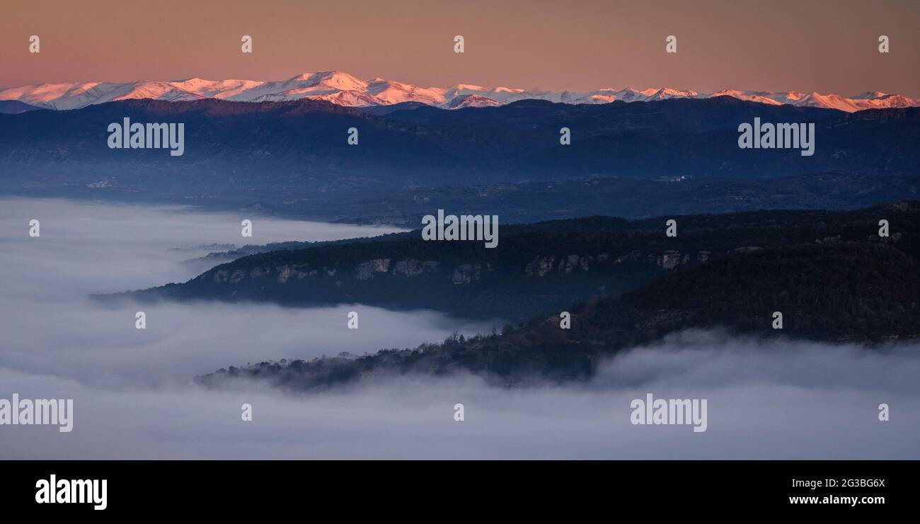 Sonnenaufgang von der Roca del Migdia Klippe mit Blick auf die Plana de Vic mit Nebel und den östlichen Pyrenäen im Hintergrund (Osona, Katalonien, Spanien) Stockfoto